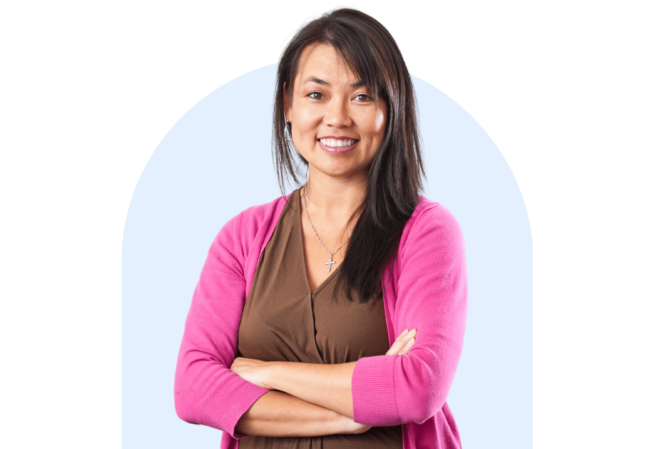 Confident female teacher smiling with arms crossed, wearing a pink cardigan and standing against a light blue background.