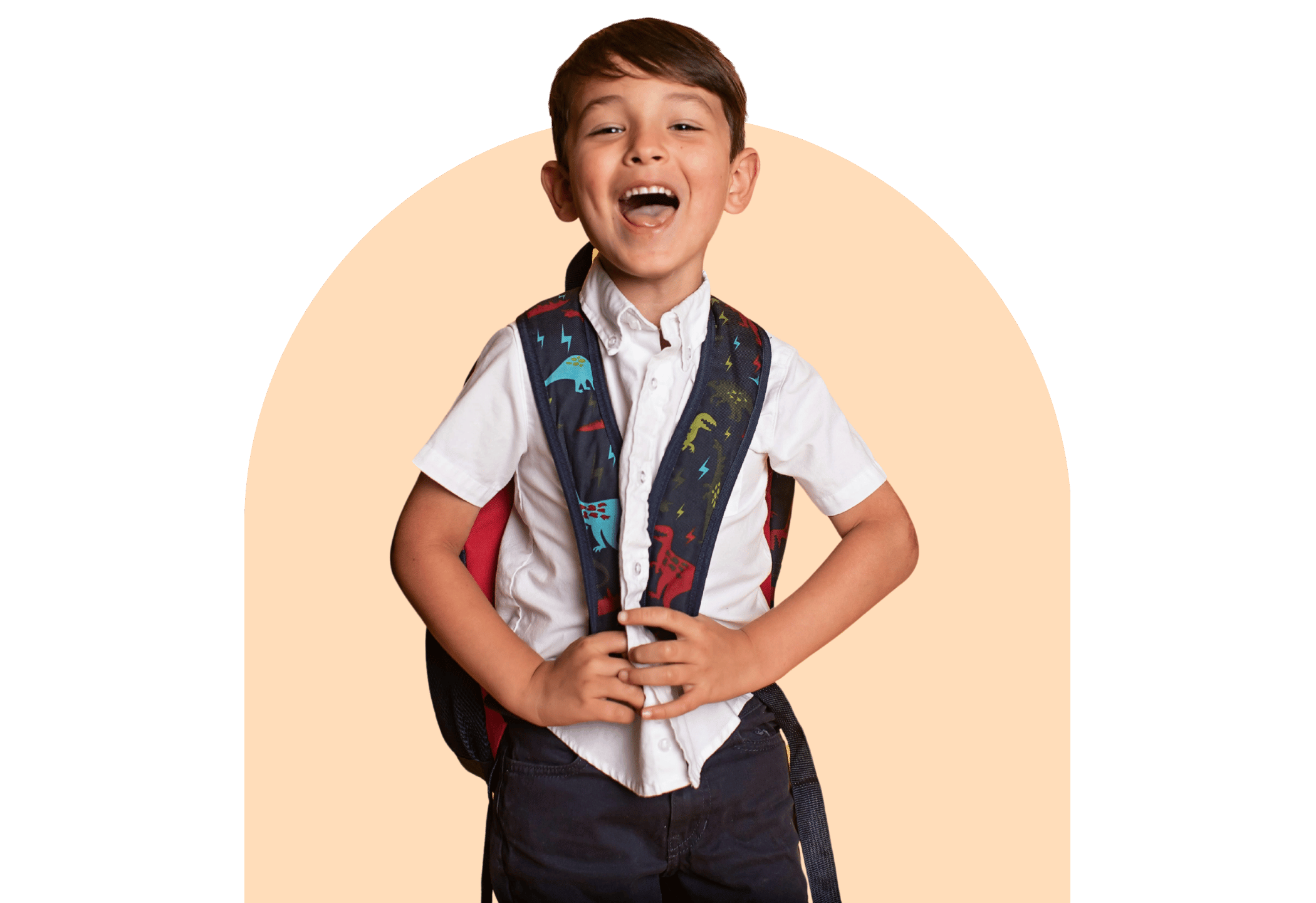 Smiling young student wearing a dinosaur backpack, standing in front of a peach background.