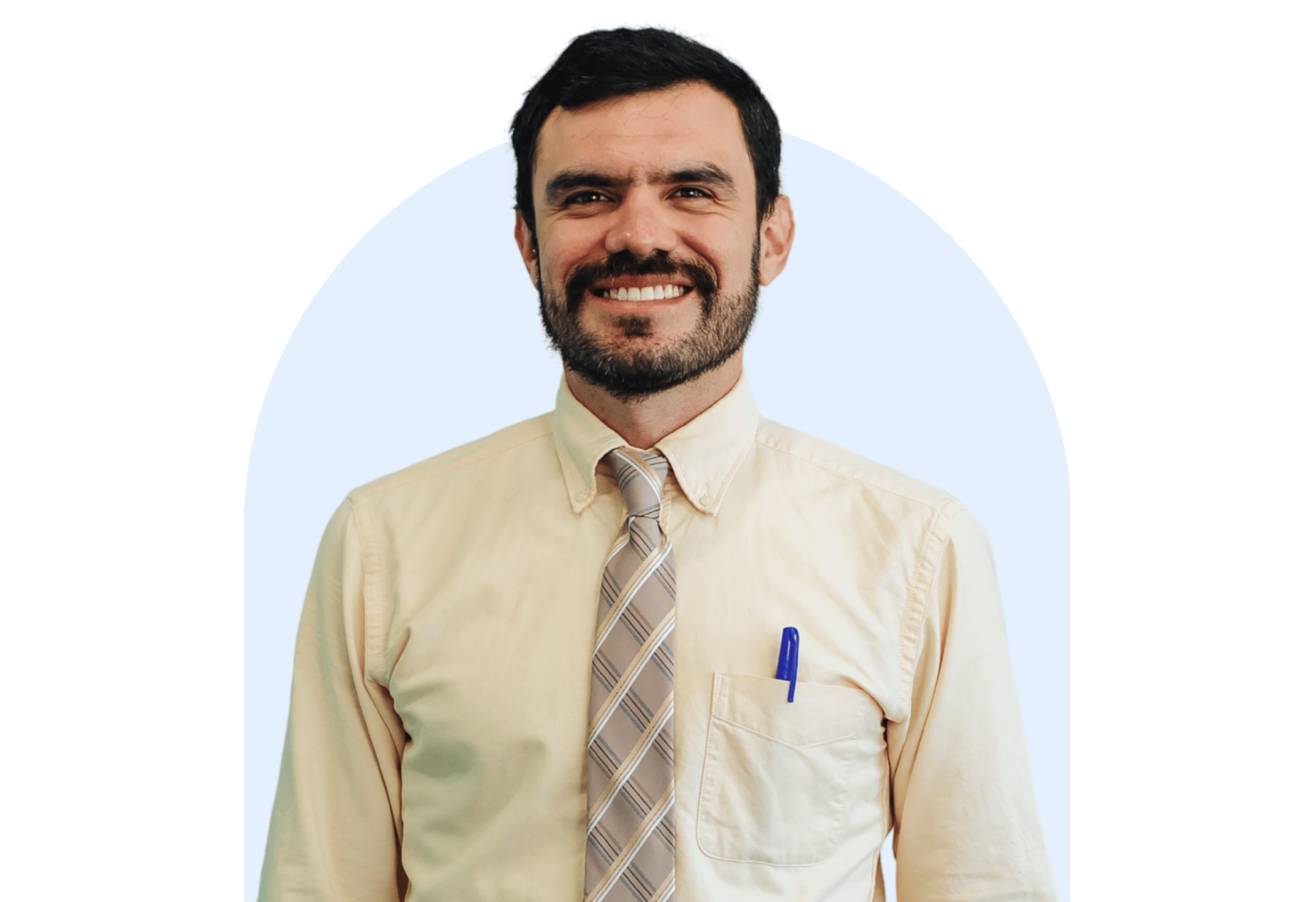 Smiling male teacher in a cream shirt and tie standing confidently in front of a light blue background.